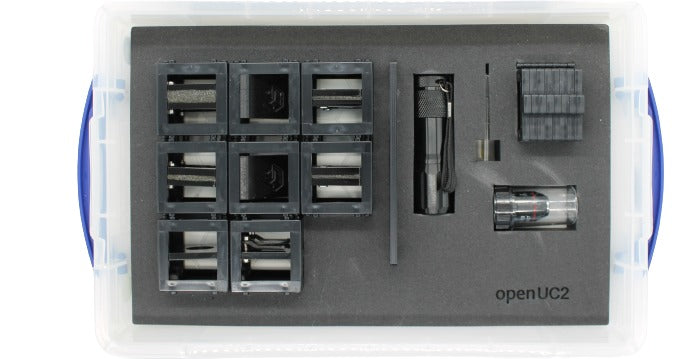 A gray UC2 Minibox with various optical components such as lenses and mirrors, designed for microscopy and imaging experiments.